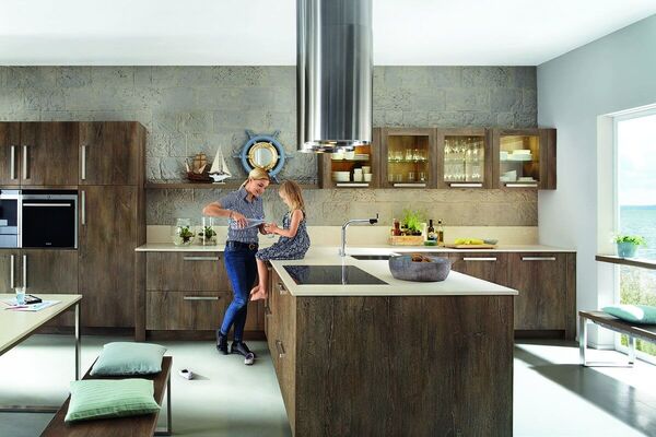 Moderne Einbauküche in Holzoptik, Mutter und Kind bereiten gemeinsam Essen am Küchenblock zu.