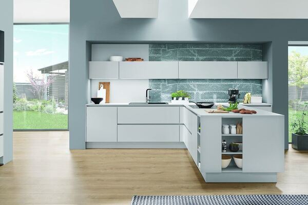 Moderne, helle Einbauküche mit Kochinsel, großen Fenstern und stilvollem Design.