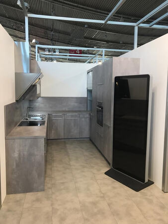 Moderne Einbauküche mit grauen Fronten, Einbaugeräten und großem schwarzen Kühlschrank.