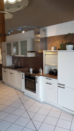 Moderne Einbauküche mit weißen Fronten, brauner Arbeitsplatte und stilvoller Deko.