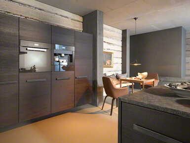 Moderne Einbauküche mit dunklen Holzfronten und Essbereich in stilvollem Design.